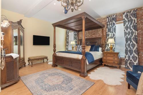 a bedroom with a canopy bed and a tv at Beland Mansion-Royal Crown suite! in Fort Smith