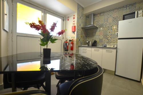 a kitchen with a table with a vase of flowers on it at Rooms DP Setúbal in Setúbal