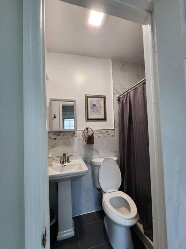 La salle de bains est pourvue de toilettes blanches et d'un lavabo. dans l'établissement Cozy studio in a lovely area, à Forest Hills