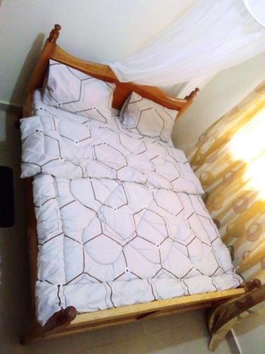 a bed with white sheets on it in a room at Selitah Apartments in Kitale