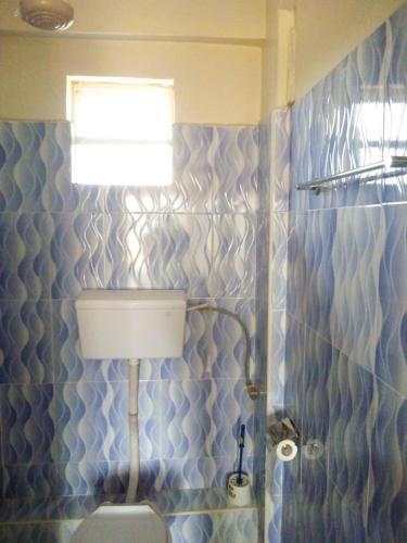 a blue tiled bathroom with a toilet and a window at Selitah Apartments in Kitale