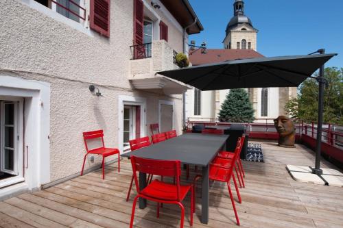 un tavolo nero con sedie rosse e un ombrellone su una terrazza di OURAL Annecy Rent Lodge ad Annecy