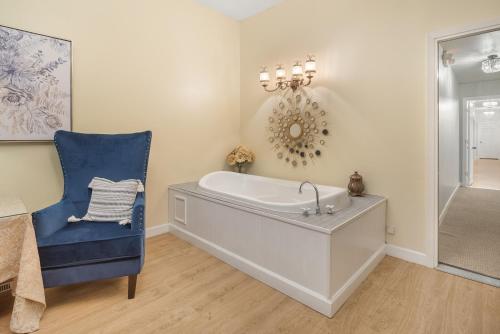 bagno con vasca e sedia blu di Grand Mansion-Royal Crown suite! a Fort Smith