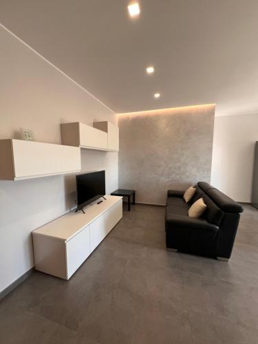 a living room with a black couch and a television at La dimora di Serenella in Montescaglioso