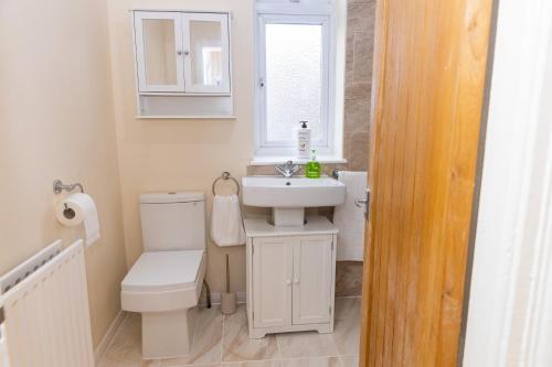 uma casa de banho com um WC, um lavatório e uma janela em Fortune 24 house em Rainham