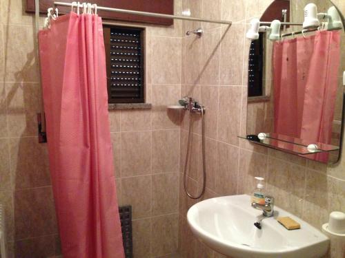 a bathroom with a pink shower curtain and a sink at Casa Dos Cabecinhos in Paradamonte
