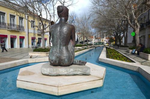 a statue of a woman sitting on a rock in a fountain at Suites DP Setúbal in Setúbal