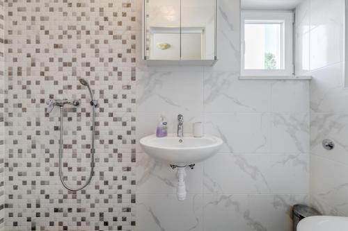 a white bathroom with a sink and a shower at Apartments Podstrana with shared Pool in Podstrana