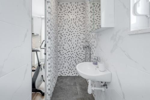 a white bathroom with a sink and a shower at Apartments Podstrana with shared Pool in Podstrana