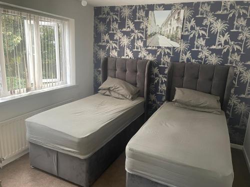 a bedroom with two beds in a room with wallpaper at 4 Bed Comfy House in Birmingham in Birmingham