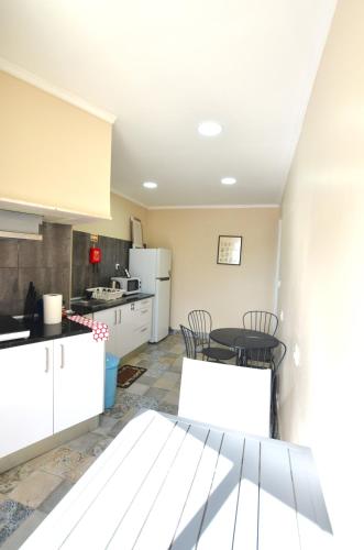 a kitchen with white cabinets and a table and chairs at Suites DP Setúbal in Setúbal