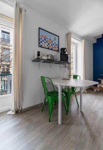 une salle à manger avec une table blanche et des chaises vertes dans l'établissement Les Stins - Appartements climatisés - centre ville, à Vichy