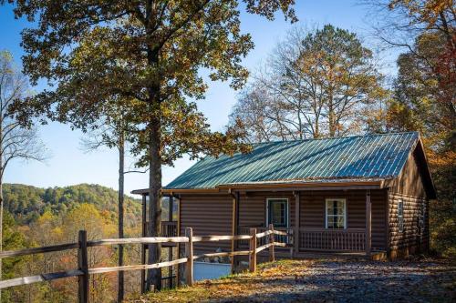 a wooden cabin in the woods with a fence at Cozy Cabin: w/ Balcony, Pool Table, Fire pit & BBQ in Mineral Bluff