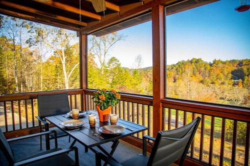 a table and chairs on a balcony with a view of trees at Cozy Cabin: w/ Balcony, Pool Table, Fire pit & BBQ in Mineral Bluff