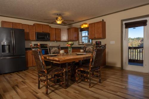 a kitchen with a wooden table with chairs and a refrigerator at Cozy Cabin: w/ Balcony, Pool Table, Fire pit & BBQ in Mineral Bluff