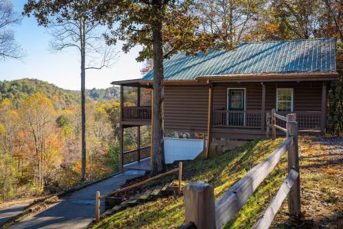 a log cabin with a porch and a fence at Cozy Cabin: w/ Balcony, Pool Table, Fire pit & BBQ in Mineral Bluff
