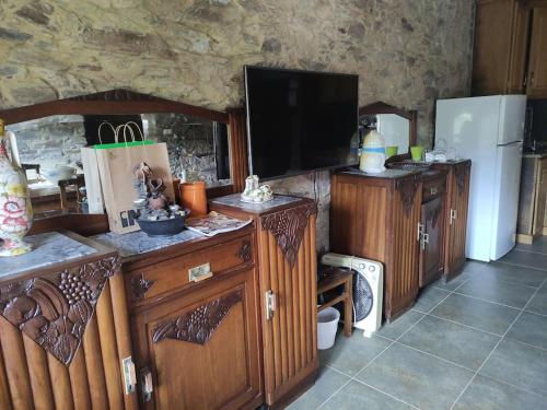 a kitchen with wooden cabinets and a tv and a refrigerator at Casa Nelito in Pedrógão Grande