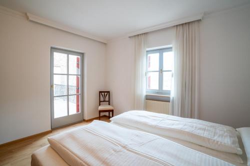 a white bedroom with a bed and two windows at Weingut Köfelgut - Turris Vini in Castelbello-ciardes