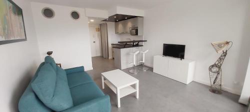 un salon avec un canapé bleu et une table dans l'établissement Studio Cosy - La plage à pied, à Capbreton