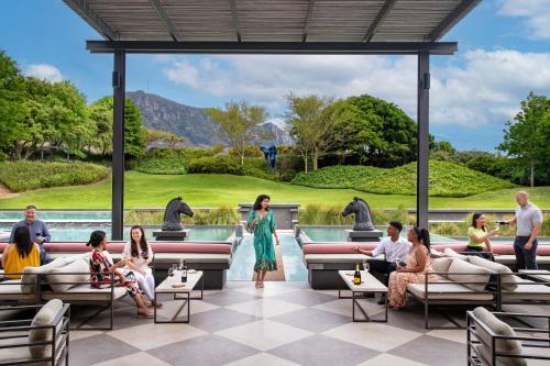 een groep mensen die rond een zwembad in een resort zitten bij Steenberg Hotel & Spa in Tokai