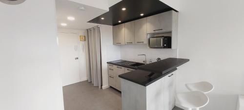 une petite cuisine avec un évier et un micro-ondes dans l'établissement Studio Cosy - La plage à pied, à Capbreton