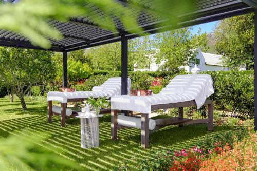 three white chairs under a gazebo in a garden at Steenberg Hotel & Spa in Tokai