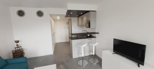 Il comprend un salon avec une télévision et une cuisine avec des tabourets. dans l'établissement Studio Cosy - La plage à pied, à Capbreton