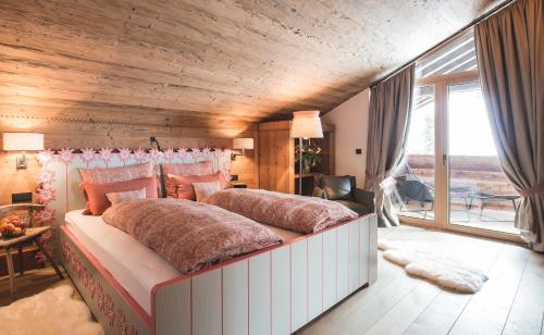 a bedroom with a large bed with a wooden ceiling at Lech Lodge - 3 Chalets und eine "Gute Fee" in Lech am Arlberg