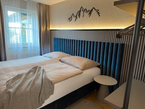 a bedroom with a bed with a blue head board at Apartment Sonntagskind in Seekirchen am Wallersee