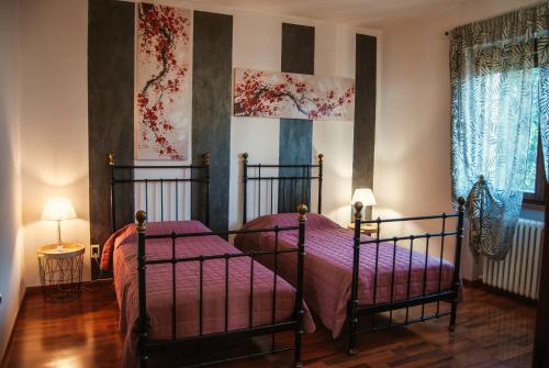 a bedroom with two beds and paintings on the walls at WELCOME TRAVELLER FRIDA's APARTMENt in Caprino Veronese