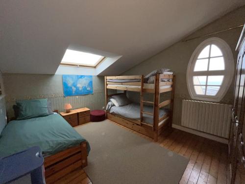 Cette chambre mansardée comprend 2 lits superposés et une fenêtre. dans l'établissement Maison 5 chambres vue sur mer Donville-2kms Granville, à Donville-les-Bains