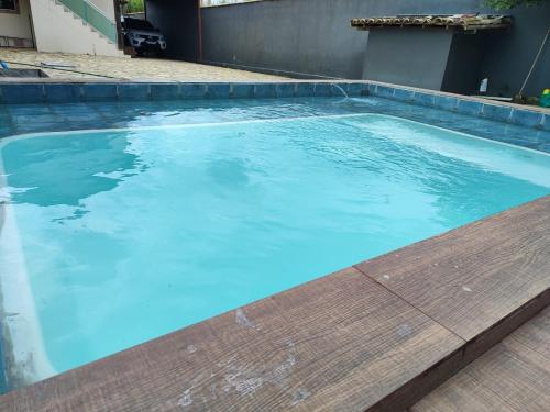 einen Pool mit blauem Wasser und eine Holzterrasse in der Unterkunft Casa temporada in Búzios