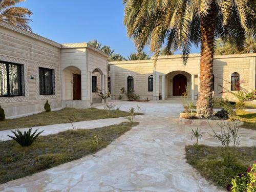 una casa con una palmera y un camino de entrada en مزرعة المدائن, en Madain Saleh