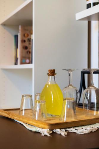 a wooden tray with four glasses and a yellow bottle at Sorelle di Riviera in Syracuse