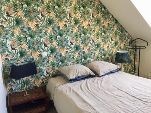 a bedroom with a large bed with a tropical wallpaper at Séjour au coeur des Pyrénées in Bagnères-de-Bigorre