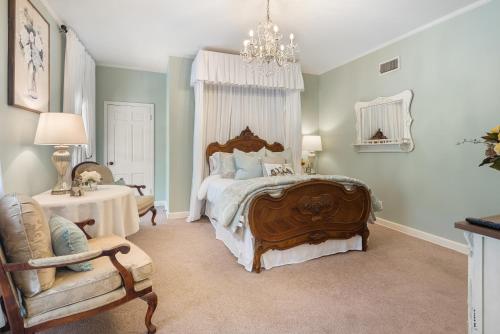 a bedroom with a bed and a chair and a chandelier at Grand Mansion-Magnolia suite! in Fort Smith