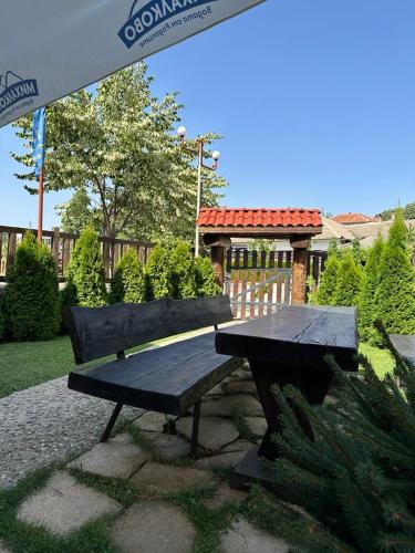 a picnic table and a bench under an umbrella at БЯЛАТА КЪЩА in Kirkovo