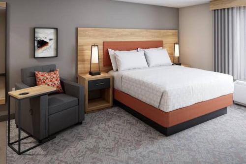 a hotel room with a bed and a chair at Candlewood Suites Sugarland Stafford in Houston