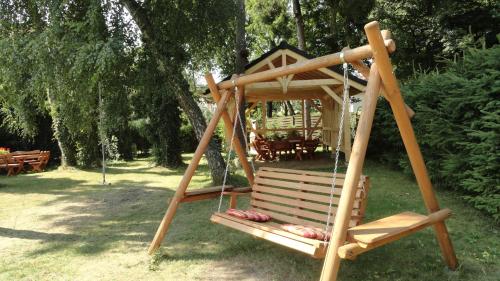 eine hölzerne Schaukel in einem Park mit einem Baum in der Unterkunft Dom Artusa in Ustka