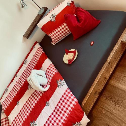 a bed with a red and white quilt on it at Conny's B&B in Niederweningen