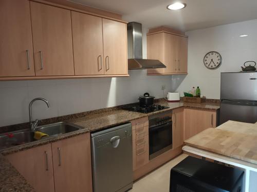 Una cocina con gabinetes de madera y electrodomésticos de acero inoxidable. en La Mar de Palamós Suite, en Palamós