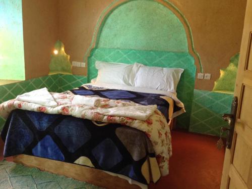 1 dormitorio con 1 cama con cabecero verde en KASBAH IFRi en Amdnarene