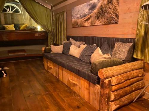 eine Couch aus Holz in einem Zimmer mit Klavier in der Unterkunft Gestrande Woonark in Erica