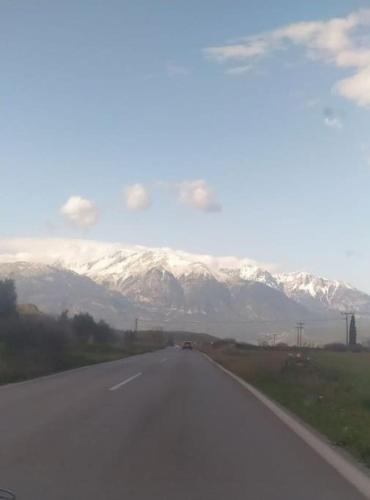 a car driving down a road with snow covered mountains at Βίλα Ελιά Παραδοσιάκο σπίτι στην Αμφίκλεια in Amfiklia