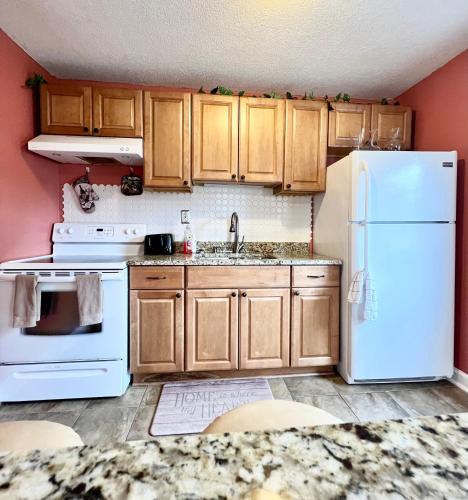 a kitchen with a white refrigerator and wooden cabinets at A Cozy Spot on Montague in Charleston