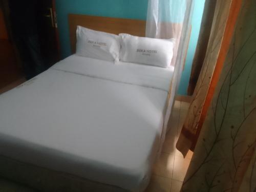 a white bed with two pillows on top of it at Deka hotel Nairobi in Thika