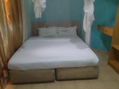 a bed with white sheets and pillows in a room at Deka hotel Nairobi in Thika