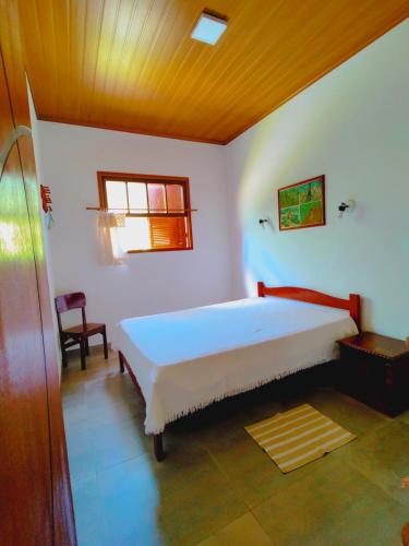 1 dormitorio con 1 cama y 1 silla en Condomínio Ypê Casas Maringá MG, en Visconde De Maua