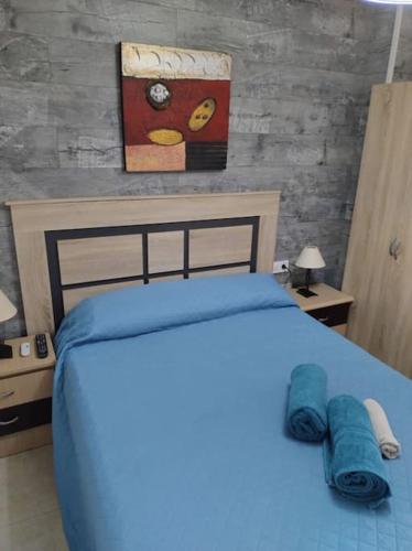 Un dormitorio con una cama azul y una pintura en la pared en La casita de la abuela en Málaga