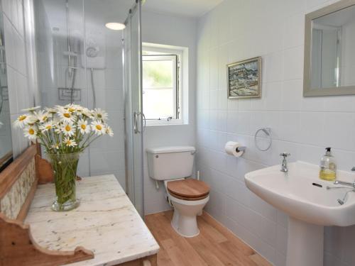 a bathroom with a toilet and a sink and a vase of flowers at 4 Bed in Litton Cheney 75851 in Long Bredy